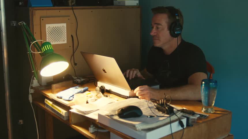 Man with headphones edits a video on his macbook pro