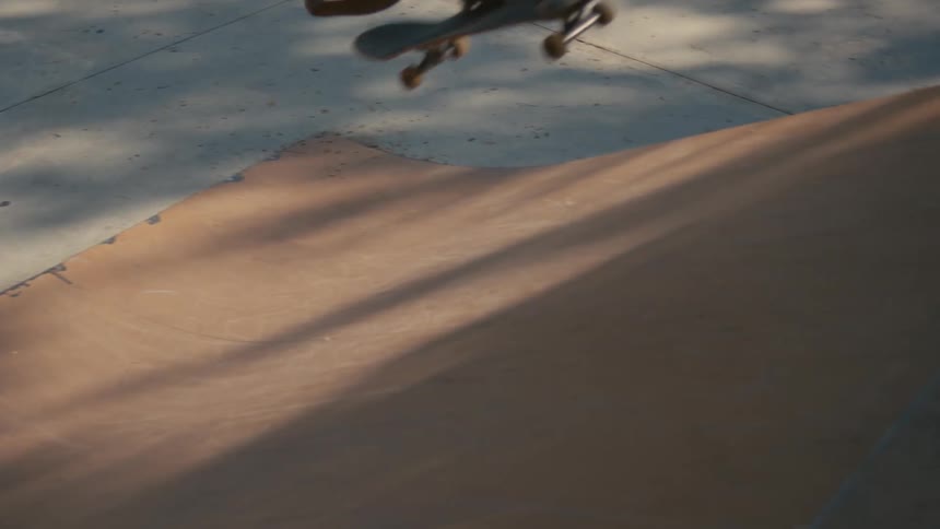 Skateboarder skates up slope in skate park an performs jump as others stand around