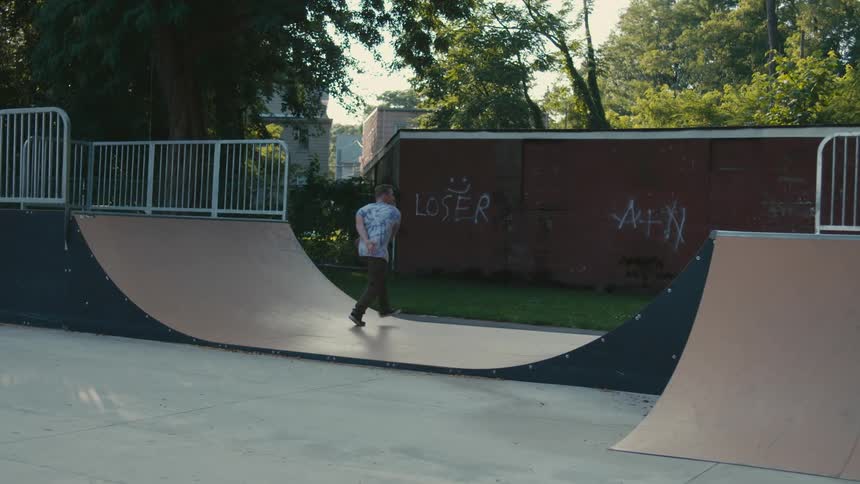 A male skateboarder skateboarding on a ramp outside