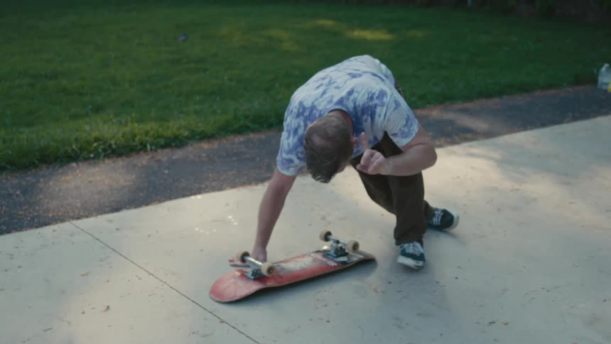 A man falls to the ground beside a skateboard in exhaustion