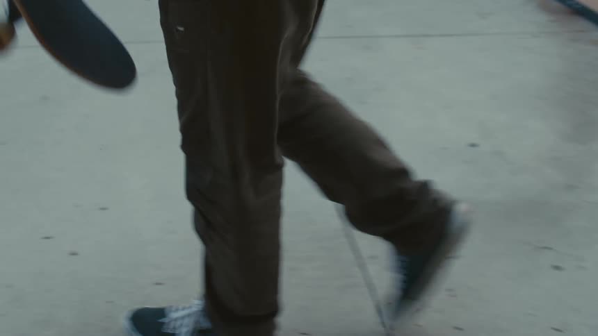 Man nods at another then gets on skateboard at skate park