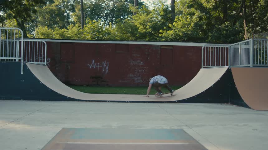 A man skateboarding on a ramp in public park falls down