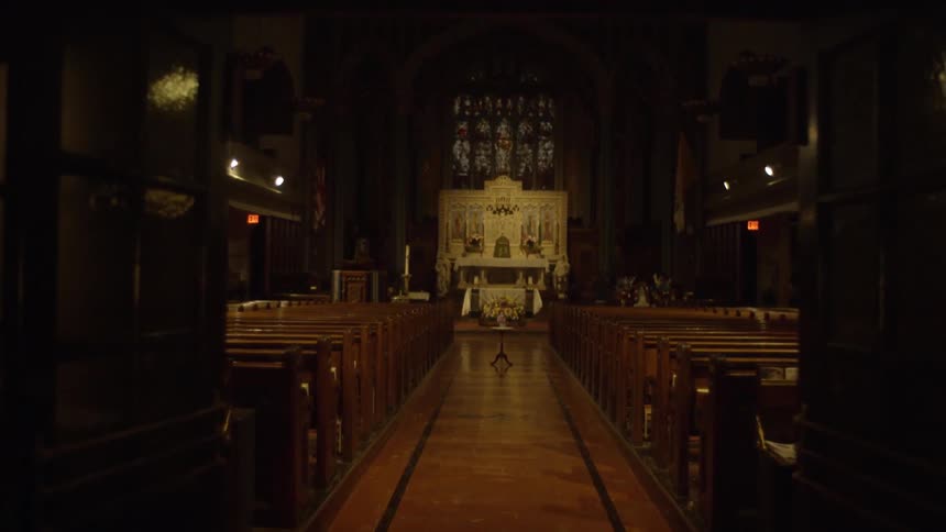 A view down a long aisle between the pews of a large church