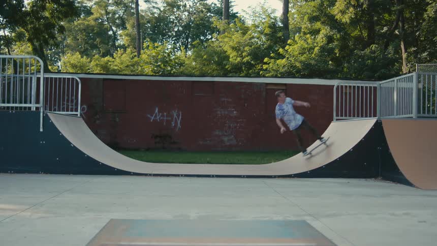 A man skateboards on a ramp in a public park