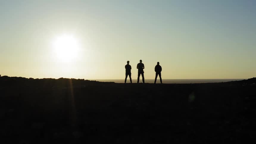 Three people are hiking outdoors at dusk