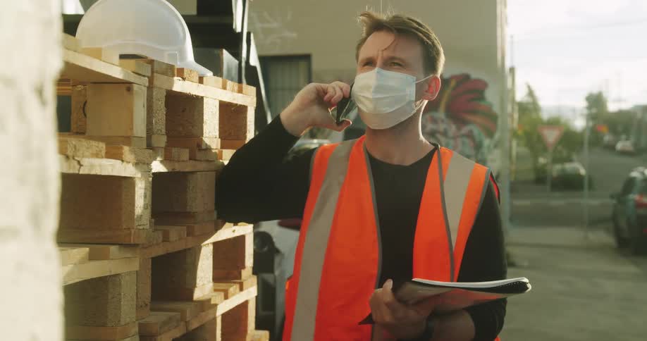 A construction worker talks on the phone as he looks at paperwork