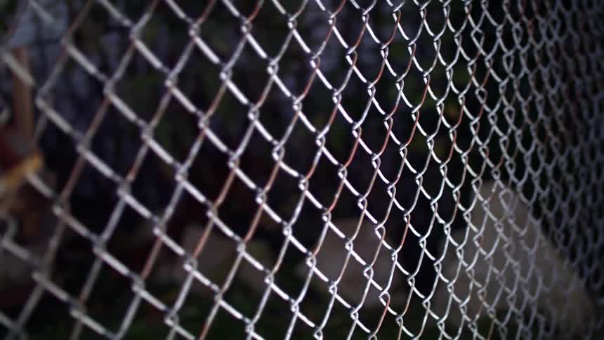 A light shines on a chain link fence