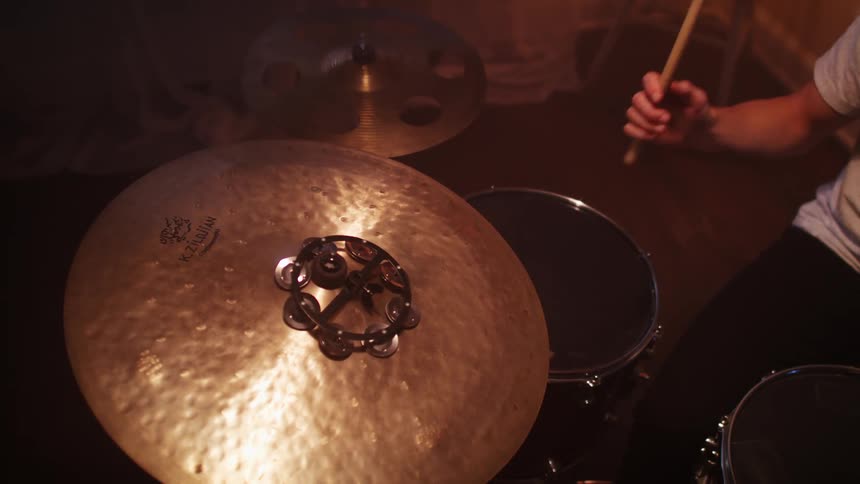 Male drummer plays a set of drums by hitting it with sticks