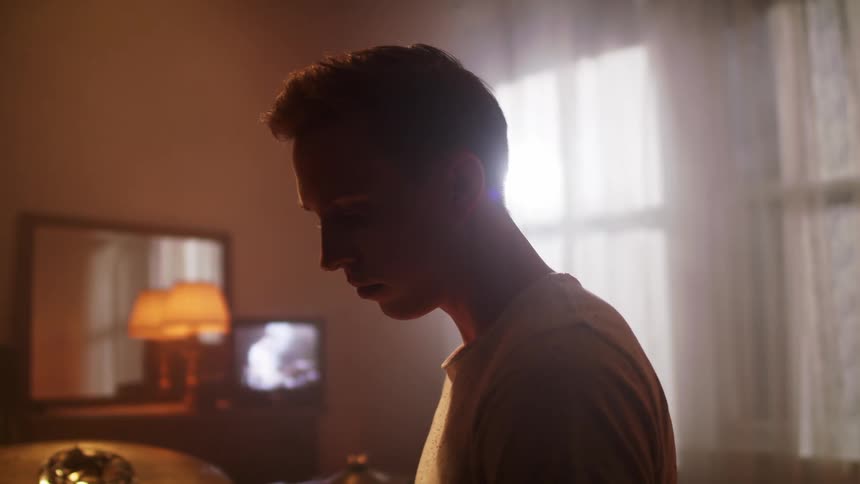 A teenage boy at home glances at the television