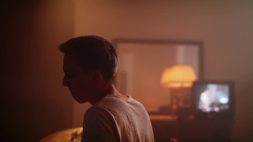 A teenager plays the drums at home while watching video of a person drumming on an old cathode television