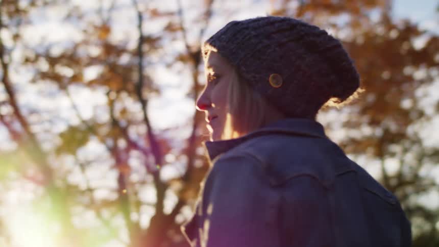 A young woman looks up at the yellowing foliage of the surrounding trees