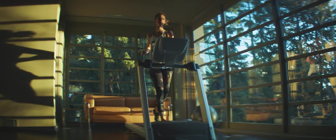 A woman runs on a treadmill in an expensive house during the day