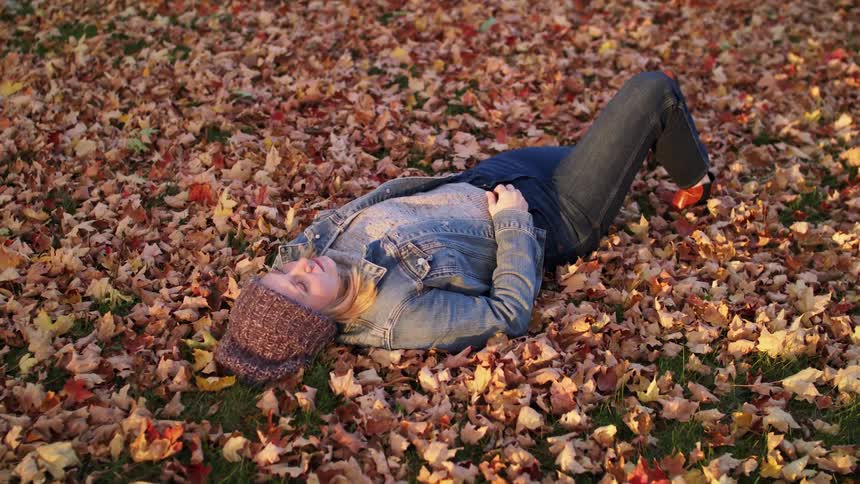 A woman is laying outdoors in the fall