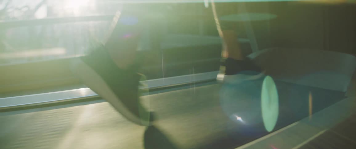 A woman running on a treadmill while sunlight shines through a window