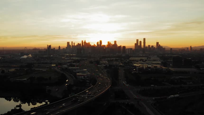 The sun setting behind silhouetted skyscrapers in a large city