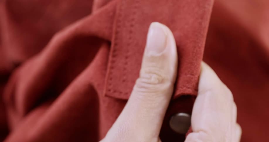 A female hand holding a light red garment with buttons