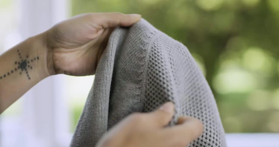 A woman runs knitted material between her fingers