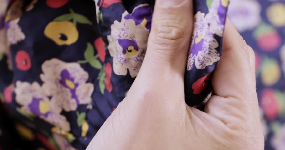 A woman holding material moves it in her hands and examines it