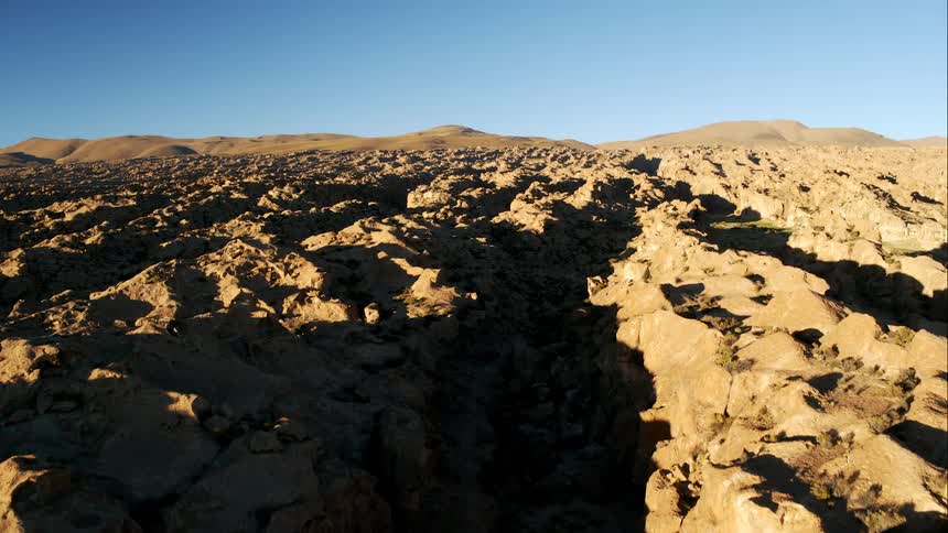 Dirt road passes through broken terrain near ravine with river course
