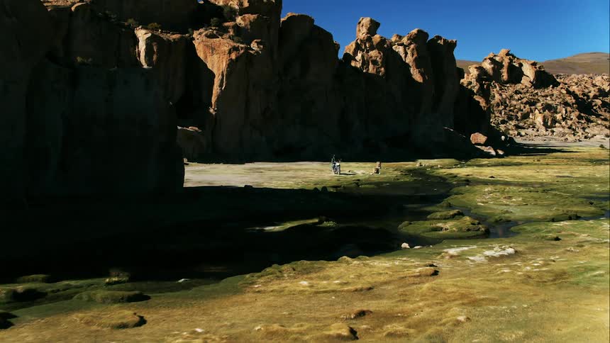 A person makes a turn near the rocks on their motorcycle