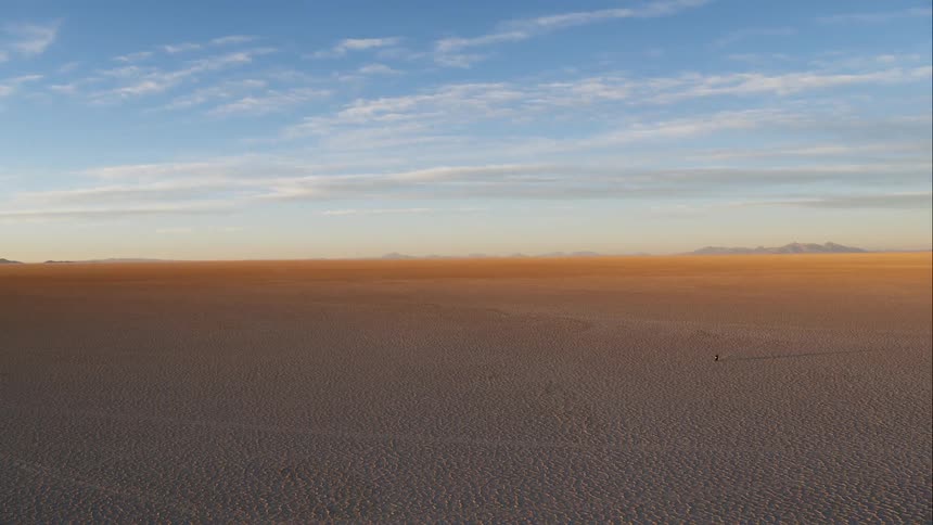 Aerial view of a motorcyclist riding a motorcycle across the large desert