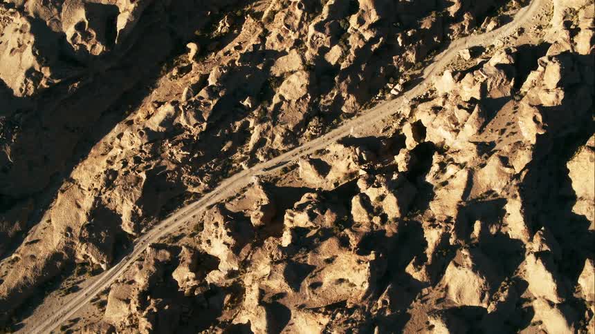 Aerial view of a car driving in a rural area is displayed