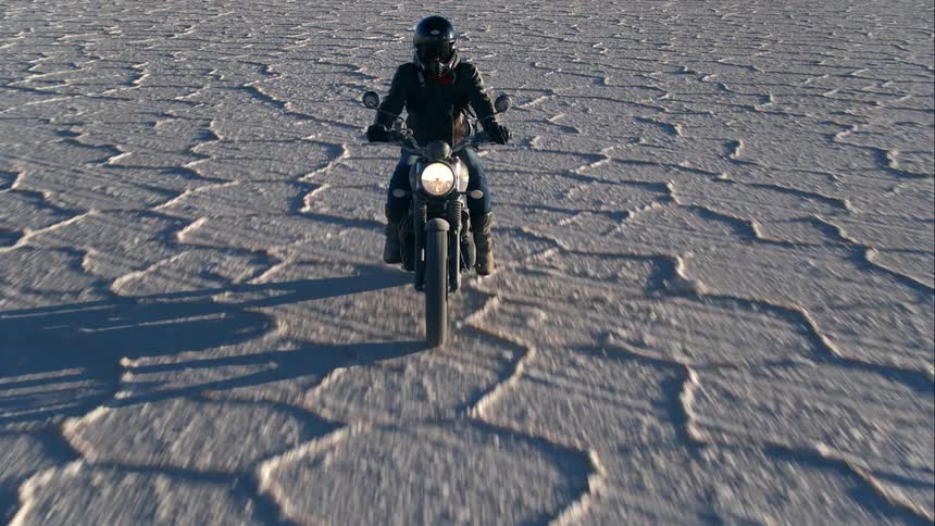 A person is riding a motorcycle outdoors in a desert