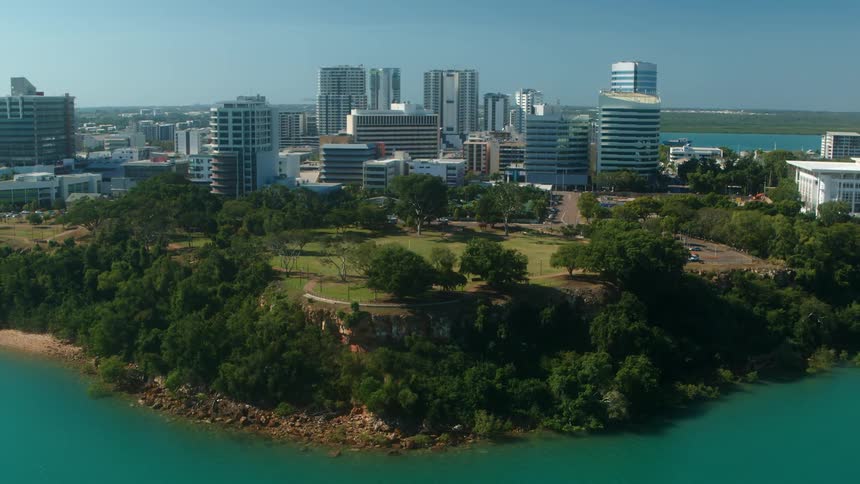 Rocky cliffs and trees surround buildings of a coastal city