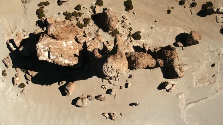 A person rides their motorcycle past a large rock formation