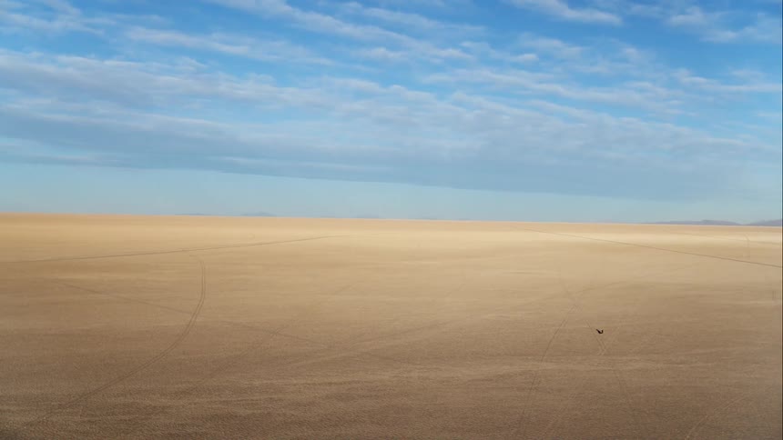 Aerial view of a motorcyclist riding a motorcycle across the large desert