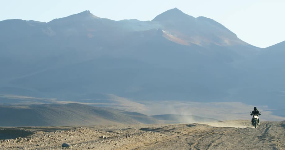 A person driving their motorcycle across the desert