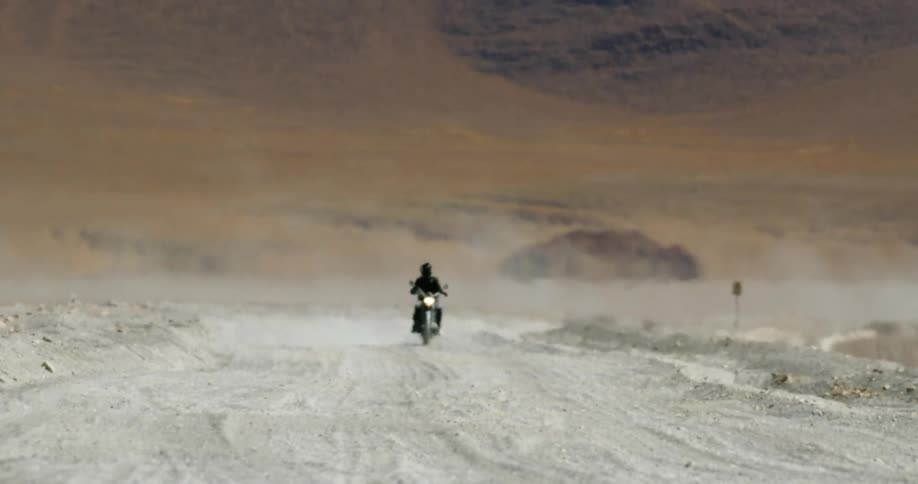 A motorcycle is traveling in the desert