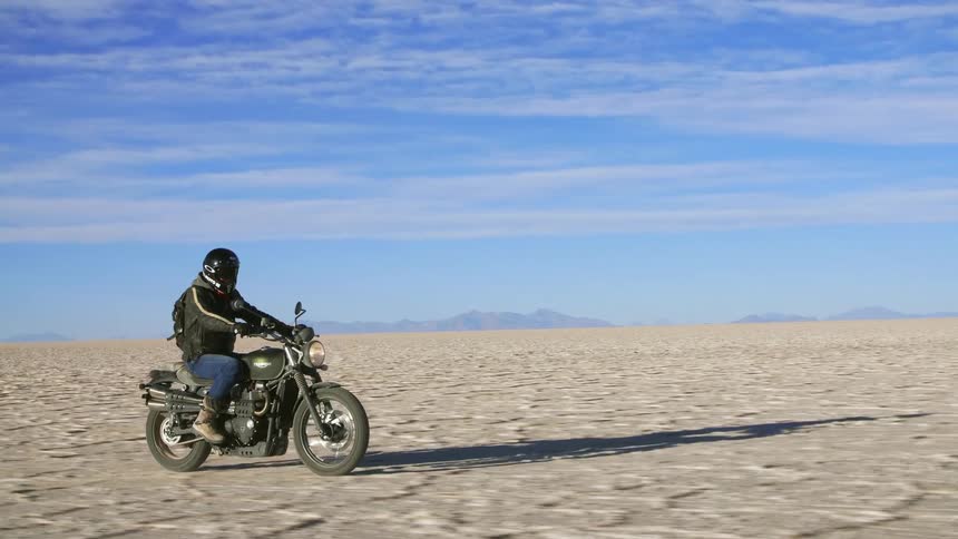 A man is riding a motorcycle in a desert