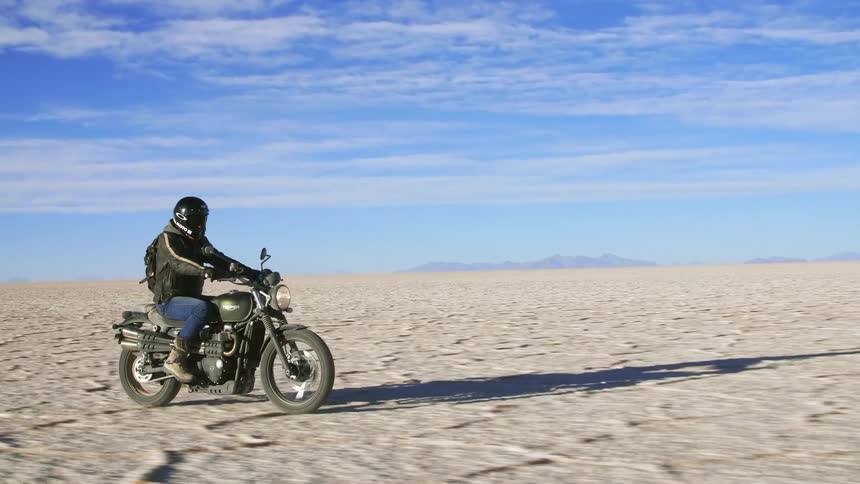 A man is driving a motorcycle in the desert