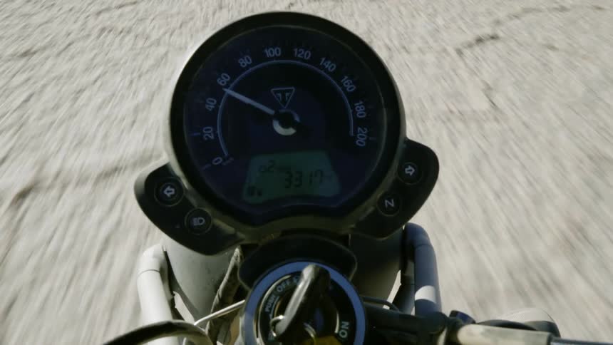A speedometer on a motorcycle speeding offroad during the day