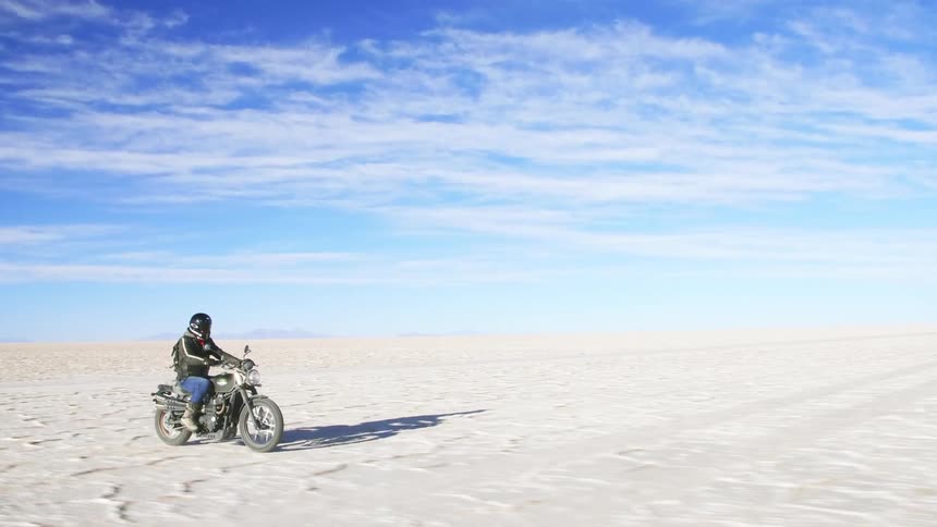 A man is riding a motorcycle through the desert
