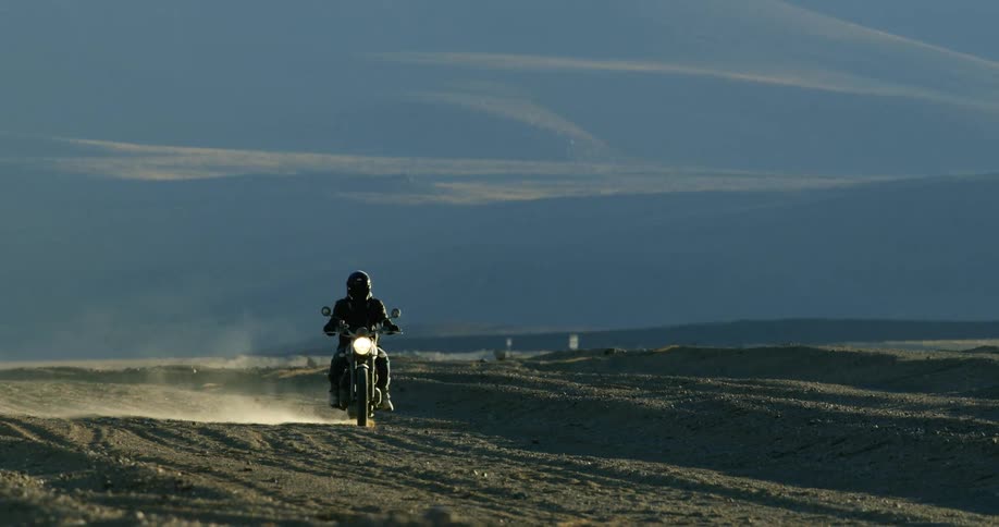 A man is riding a motorcycle on a dirt road