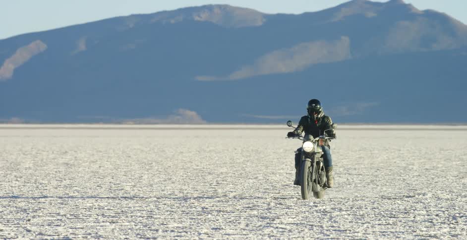 A man is riding a motorcycle in a rural area