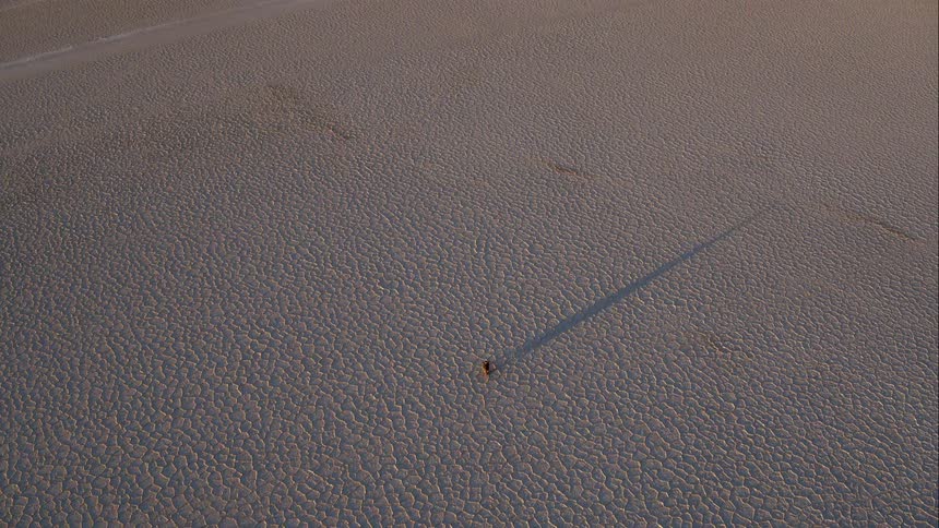 An aerial view of a person driving a motorbike across a desert
