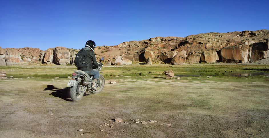 A man drives his motorcycle up to a river and stops