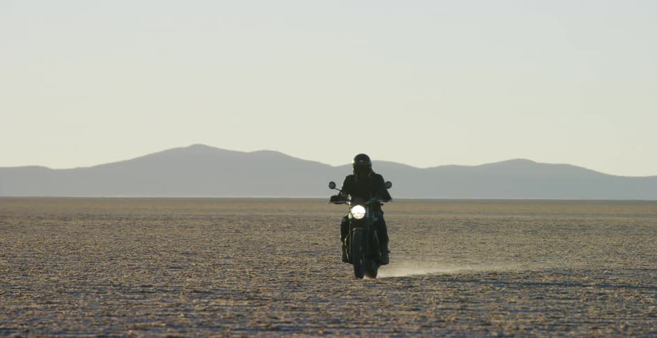 A person races their motorcycle in the desert