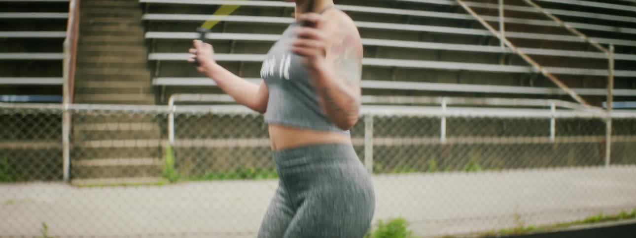 Woman jumping rope on track in front of bleachers