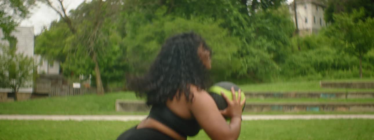 A woman jumps and throws a medicine ball