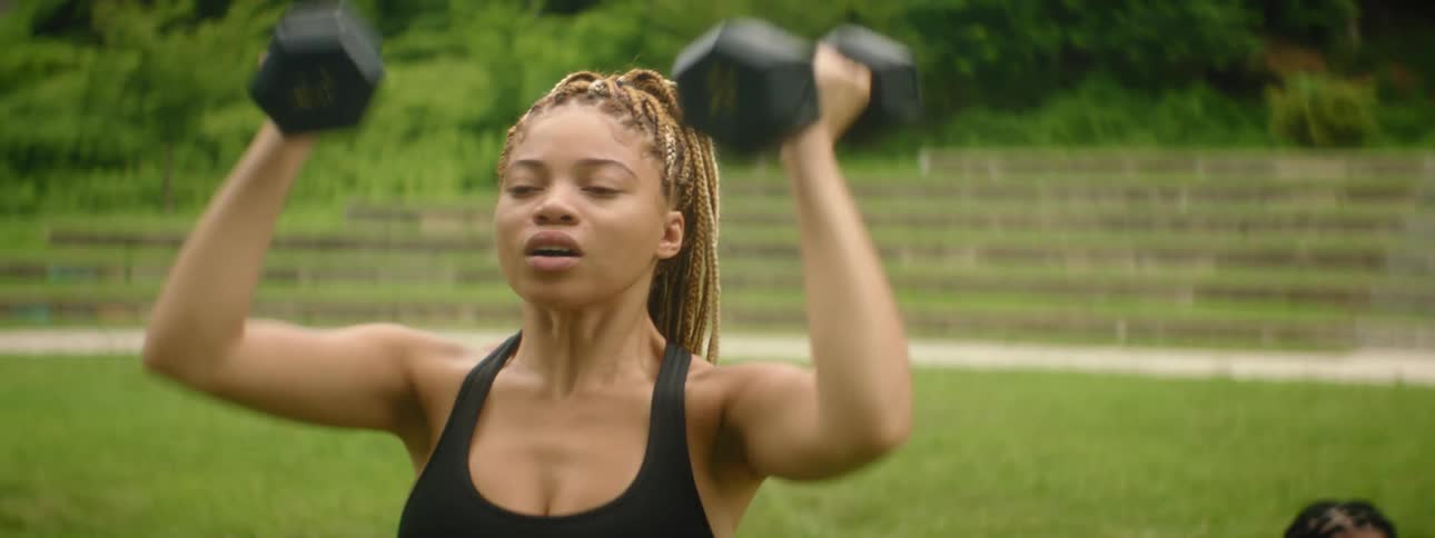 Woman lifting hand weights above head outdoors