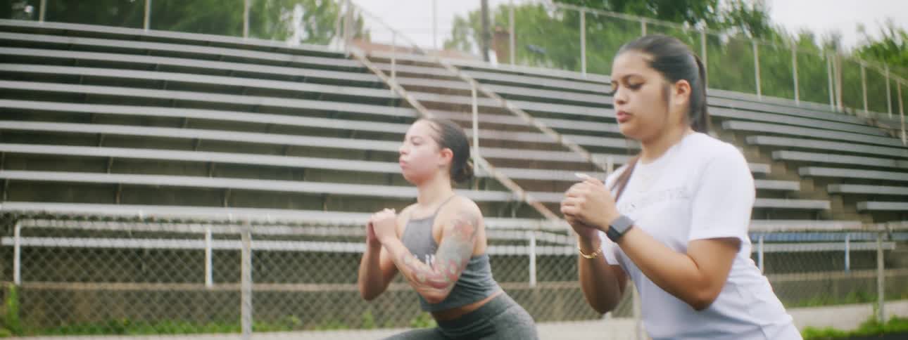 A man coaches two females on an outdoor running track