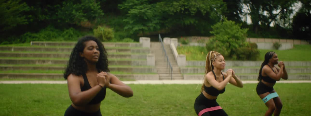 Three women participate in a athletic routine together outside