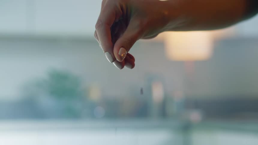 Womans hand adds a pinch of spice
