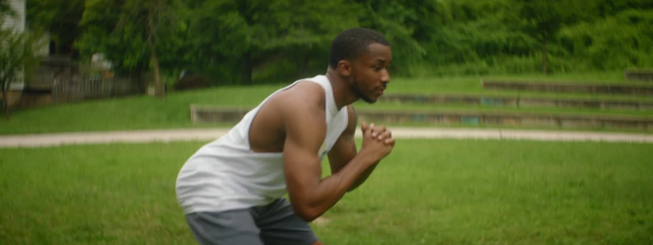 A black male and two black female exercising outside on a lawn