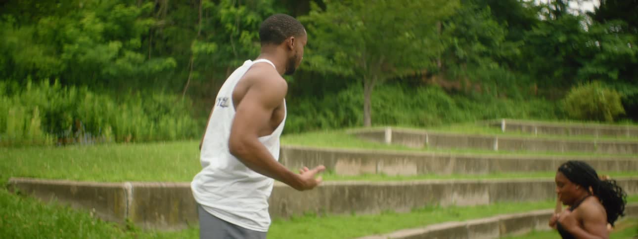 Man coaches women in workout outdoors on stone steps