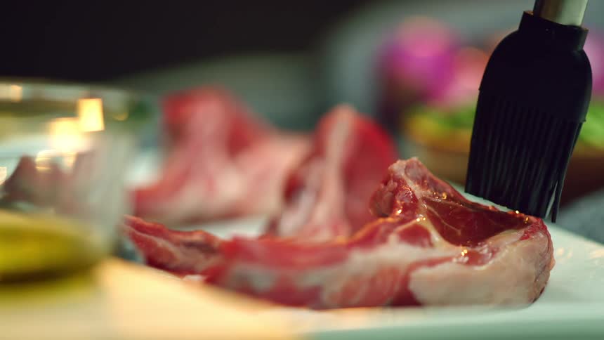 A brush is being used on a steak